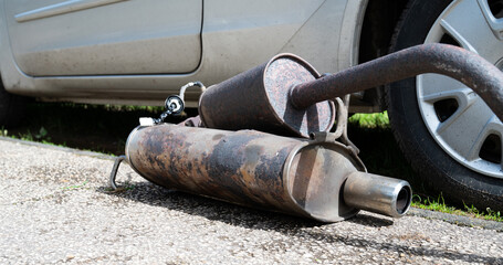Broken exhaust and muffler of a car, rusted silencer fallen down on the road, breakdown of vehicle
