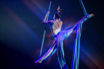 Performance by a circus acrobat artist. Girls perform aerial acrobatic elements on fabric.