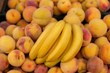 A branch of ripe bananas and peaches on the shop window.