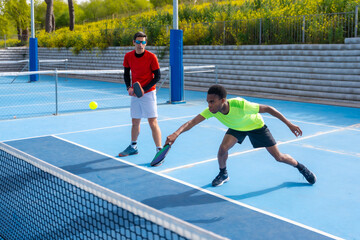 Man trying to reach the ball playing pickleball with partner