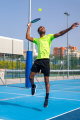 African man jumping to hit the ball playing pickleball outdoors