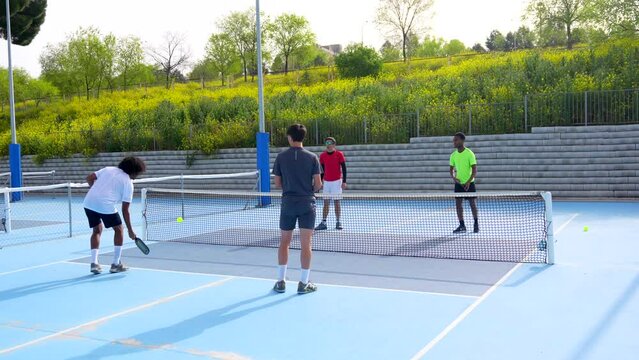 Multiracial pickleball team partners playing in an outdoor court with friends