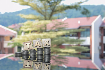 Financial and tax concept. Stacked coins on the glass table and the word TAX on wooden cubes. 