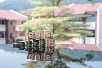 The word RISK and stacked coins reflected on the glass table. Business and risk concept