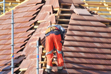 ouvrier couvreur sur un toit d'une construction - 778037012