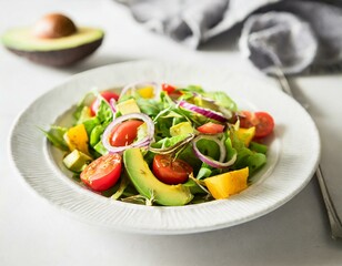 A vibrant salad featuring chunks of avocado, mixed greens, cherry tomatoes, and red onion, dressed lightly, served on a white porcelain plate, emphasizing health and freshness