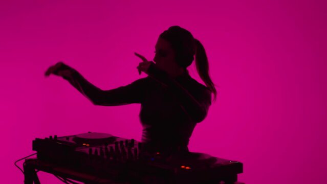 Sexy Lady With Headphones Dancing And Mixing Tracks By Modern DJ Controller In Nightclub