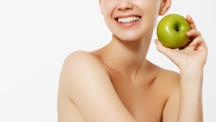 Healthy white teeth close up with an apple, isolated on white background. closeup of the face of a woman eating a green apple, isolated against white background