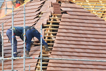 ouvrier couvreur sur un toit d'une construction - 778055227