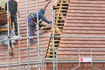 ouvrier couvreur sur un toit d'une construction - 778055228