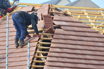 ouvrier couvreur sur un toit d'une construction - obrazy, fototapety, plakaty