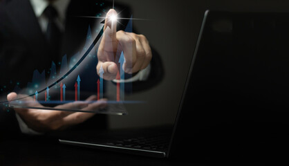 A man is pointing at a graph on a laptop screen