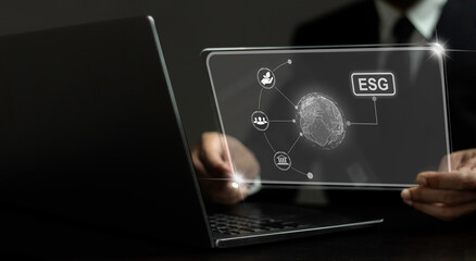 A person is holding a laptop with a screen displaying the letters ESG