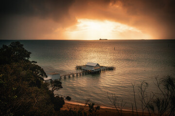The sunrise view of a pier in Millionaire's Walk in Mornington Peninsula with a ship sailing in the...
