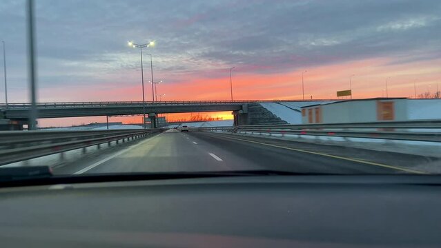 shooting a beautiful red sunset from a car moving on a highway, sunset over the bridge