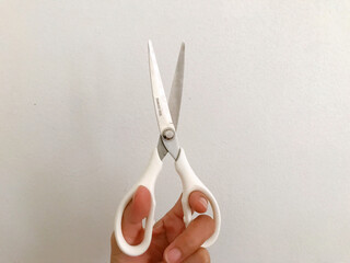 white scissors cutting a piece of paper