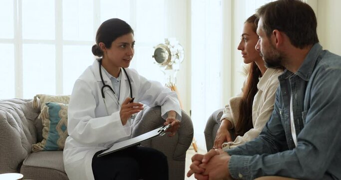 Indian woman fertility specialist in uniform provide consultation, explain treatment plan to young childless Portuguese couple during visit in private clinic. Infertility, professional medical service