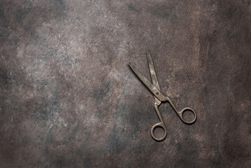 Old metal scissors on a dark grunge background. Top view, flat lay, copy space. Vintage tailor...