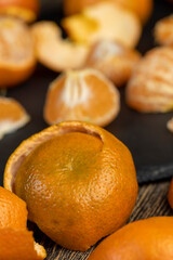 a large number of orange citrus fruits on a black slate surface