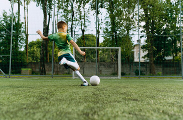 a small football player kicks the ball at the goal. The boy hits the ball. Boy Playing Soccer Game