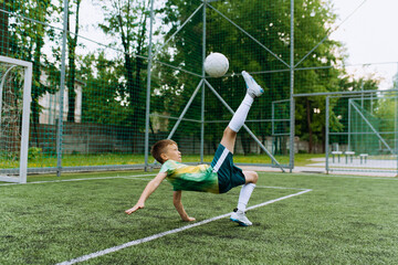 a boy, a football player, kicks the ball through himself. Kick on the soccer goal