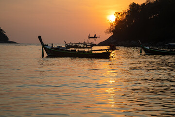 Beautiful sunset on the island of Phuket. The sun is setting. Colorful sky. Silhouettes of boats in the water.