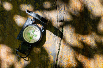 Old compass on the background of the old wooden planks. shadows of leaves. direction-finding compass