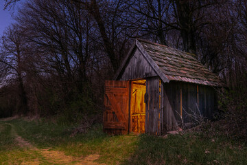 Warmes, gelbes Licht dringt durch die offene Tür einer Holzhütte