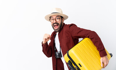 Traveler man man with beard holding a suitcase over isolated white background running fast