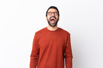 Caucasian handsome man with beard over isolated white background shouting to the front with mouth...
