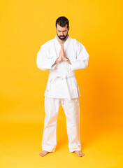 Full-length shot of man over isolated yellow background doing karate and saluting