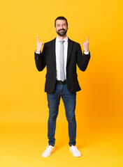 Full-length shot of business man over isolated yellow background pointing up a great idea - 778099084