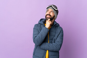 Skier man with snowboarding glasses over isolated purple background thinking an idea while looking...