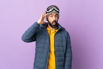 Skier man with snowboarding glasses over isolated purple background has realized something and...