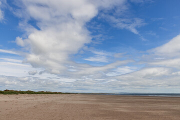 A tranquil view of St Andrews beach in Scotland, where vast stretches of sand meet the gentle embrace of the sea under a majestic sky