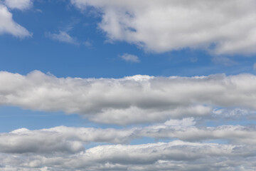 White cumulus clouds against a deep blue sky, offering a perfect backdrop or sky replacement for...