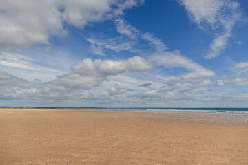 Fototapeta na wymiar At St Andrews Beach in Scotland, the golden sands stretch far into the distance, merging seamlessly with the clear blue sea under a dynamic sky