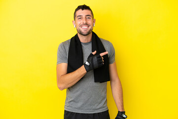 Young sport caucasian man isolated on yellow background pointing finger to the side