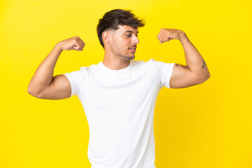 Young caucasian handsome man isolated on yellow background doing strong gesture