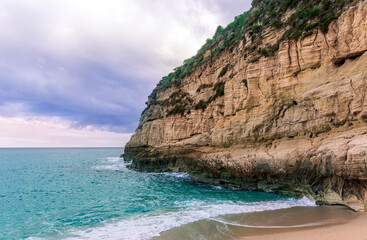 dramatic landscape of white sand beach with golden rocks and stones with beautiful rock cliff , sea surf and nice dramatic blue cloudy sky