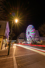 Grande roue illuminée multicolore en pleine rue la nuit à Noël