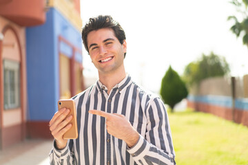 Young handsome man using mobile phone and pointing it