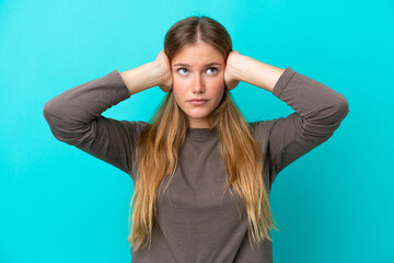 Young blonde woman isolated on blue background frustrated and covering ears