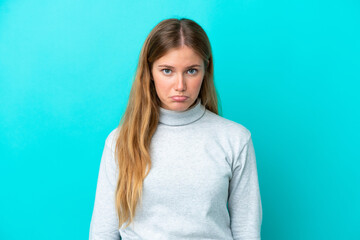 Young blonde woman isolated on blue background with sad expression