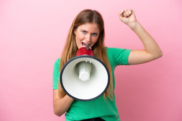 Young blonde woman isolated on pink background shouting through a megaphone to announce something