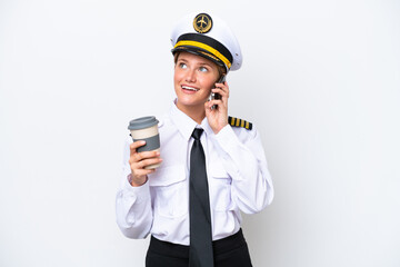 Airplane caucasian pilot woman isolated on white background holding coffee to take away and a mobile