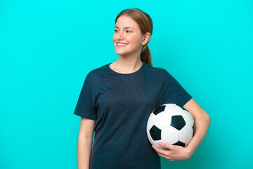 Young football player woman isolated on blue background looking to the side and smiling