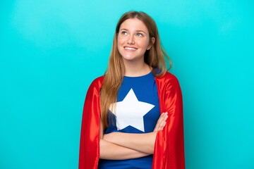 Super Hero caucasian woman isolated on blue background looking up while smiling