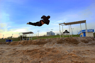 A young guy doing an acrobatic screw trick parallel to the ground against the sky from a small...