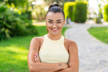 Young pretty woman with glasses at outdoors keeping the arms crossed in frontal position